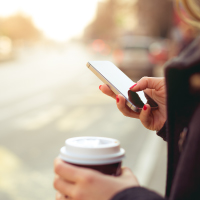 A woman with phone and coffee in hand